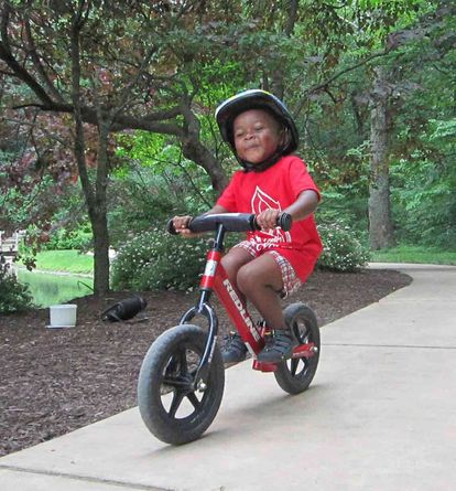 A child learns to balance on a Strider balance bike